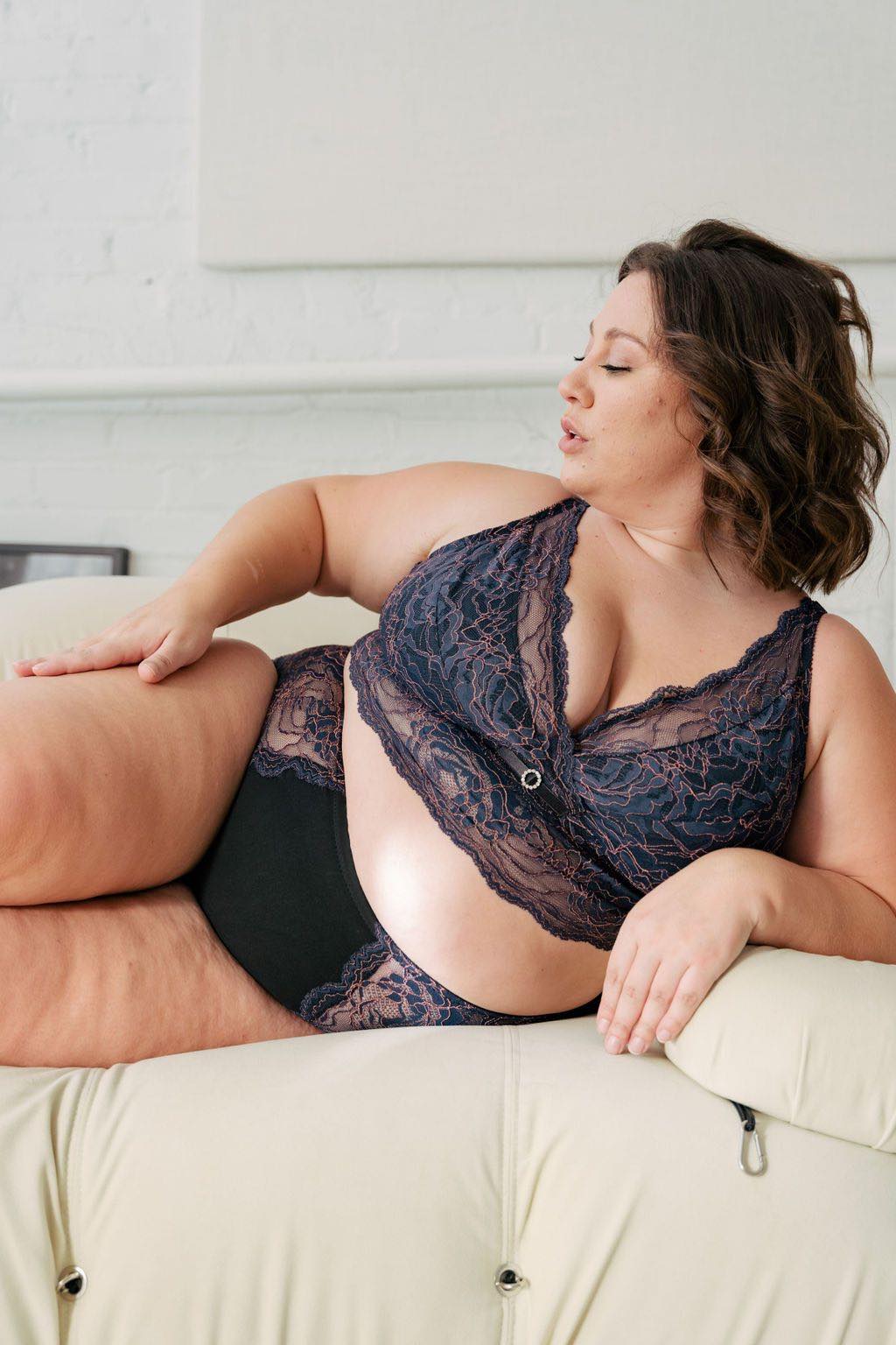 Plus size women laying on couch in blue and pink longline bra for fuller bust. #color_iris